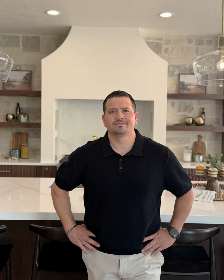 Jonathan Perez standing at the island of a modern kitchen with stone, walnut cabinetry, and marble counters.