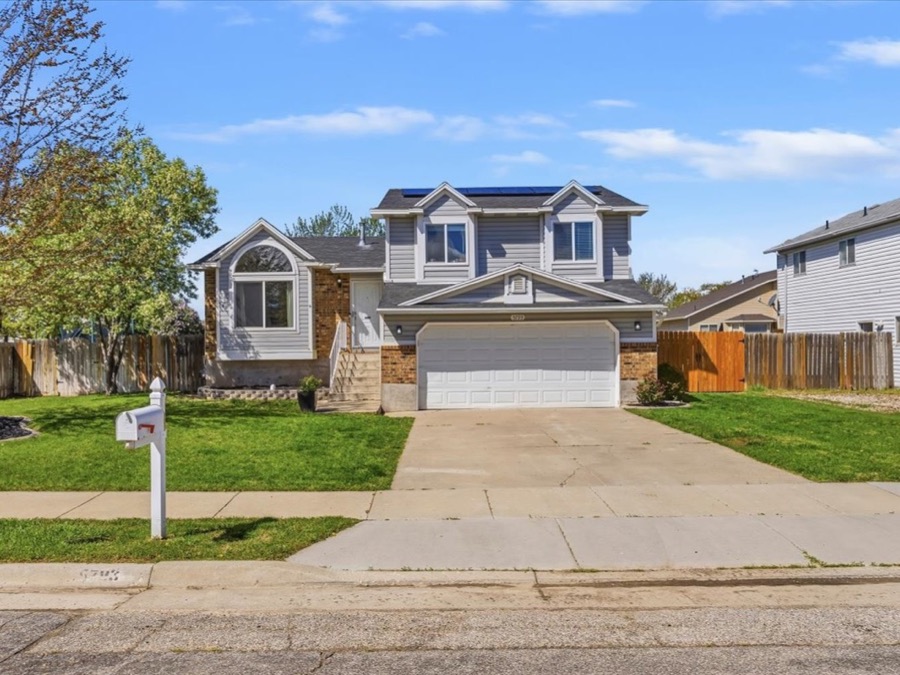 Two-story home with brick and grey siding, an arched front window, solar panels, and an attached two-car garage.
