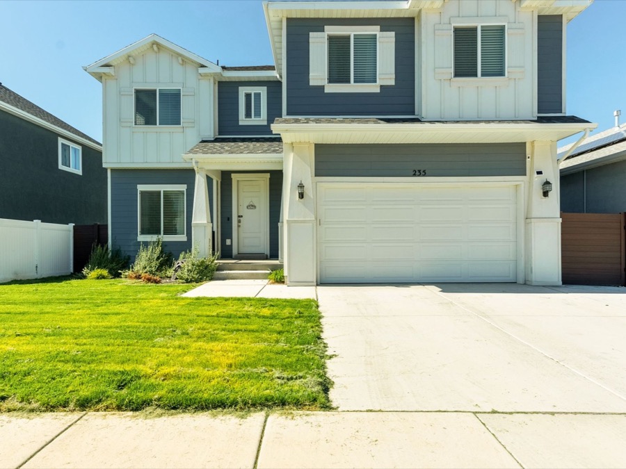 Two-storey home with blue-grey board-and-batten siding, a white two-car garage, and a green front lawn.